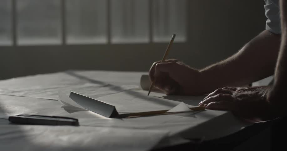 Man draws with a pencil on some paper