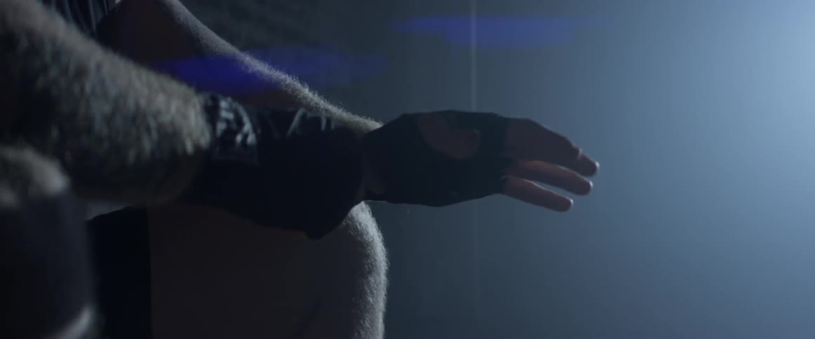 A man sits in the dark wrapping his wrist