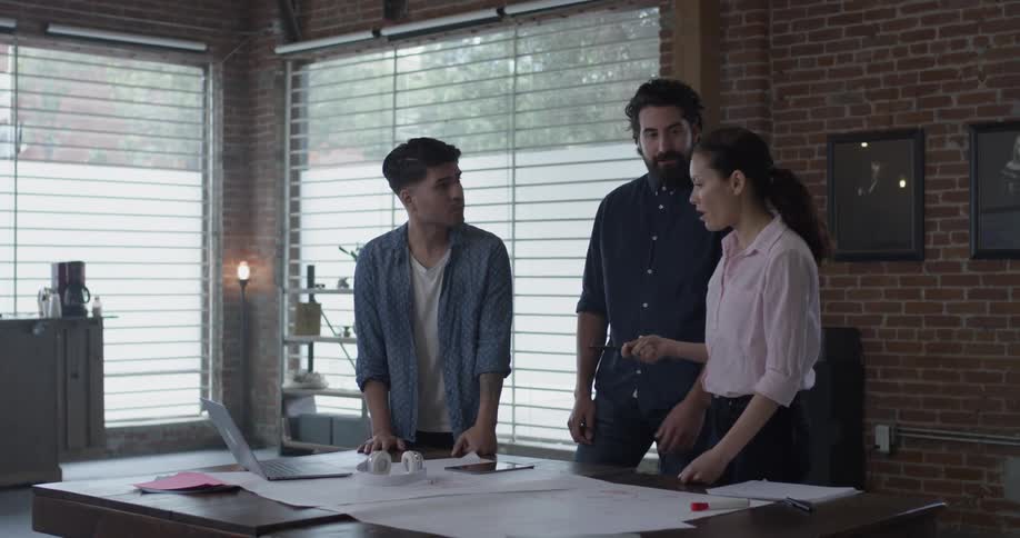 Two men and one woman discussing something on a laptop
