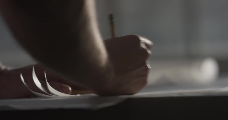 Person draws on a sheet of white paper with a pencil