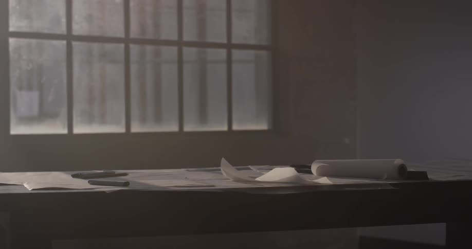 A person rolls up papers from the table and walks away