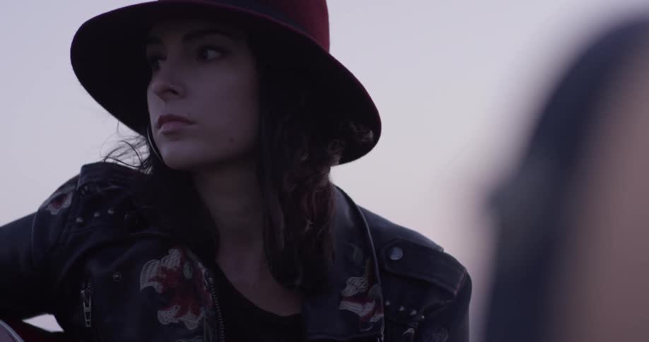 A woman sitting around outside with a red hat on