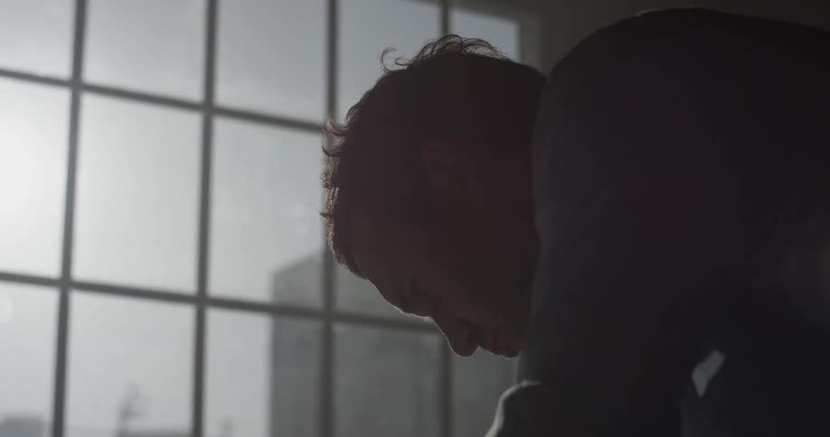 A man standing in front of a window reading a piece of paper