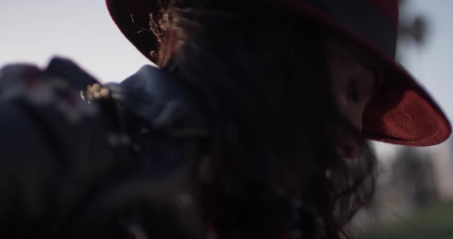 A lady with long dark hair is strumming a guitar in the park
