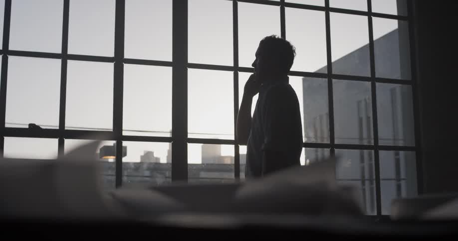 A man standing in an office talking on a cell phone