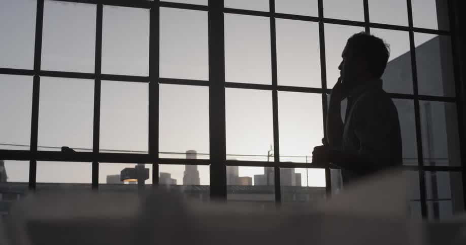 A man talking on the phone next to his window