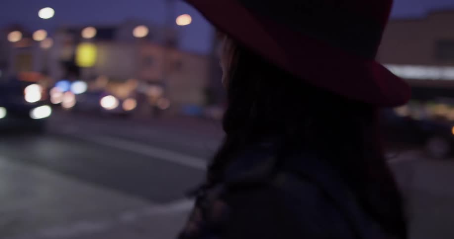 A woman that is walking down the streets at dusk