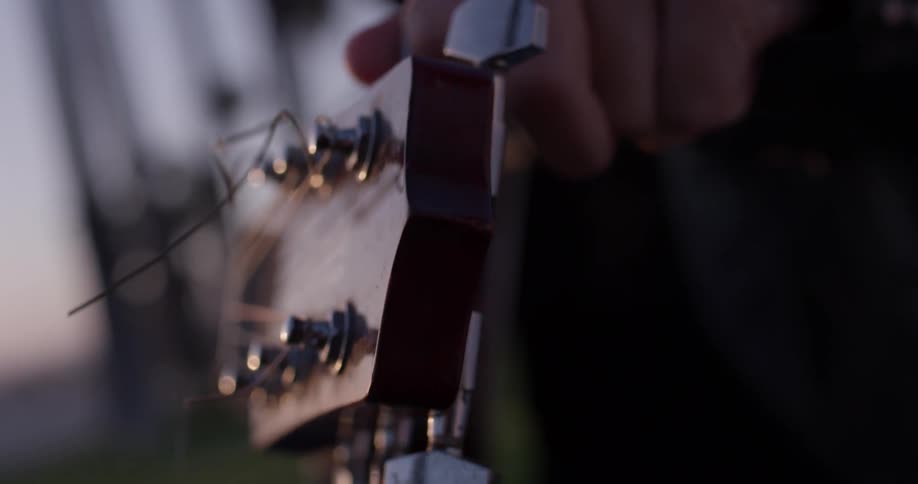 A person that is adjusting the tuning on a guitar