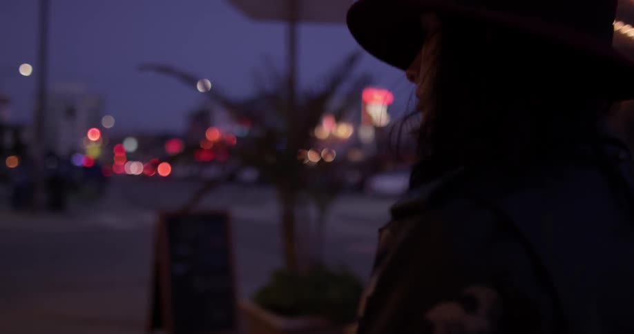 A woman walking down the sidewalk with a guitar case