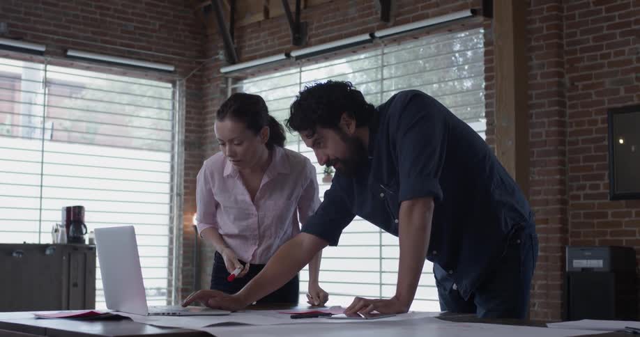 A man and woman looking over a design and talking