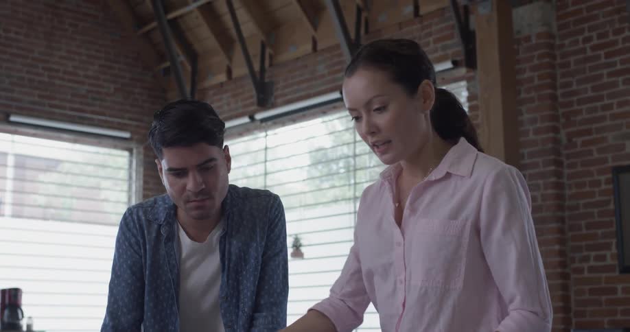 A woman writes something and a man points to another area of the table