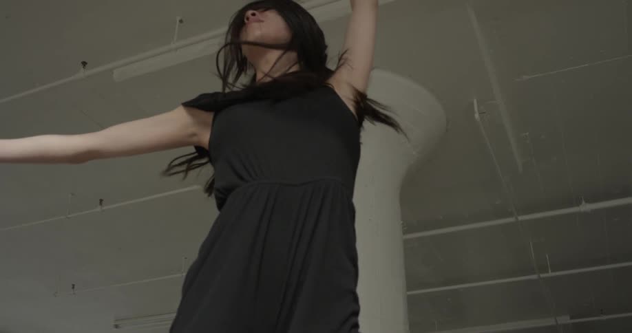 A woman in a black jumpsuit jumping into the air