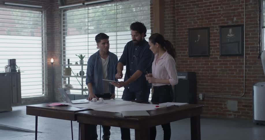Two men and one woman looking at something on a tablet