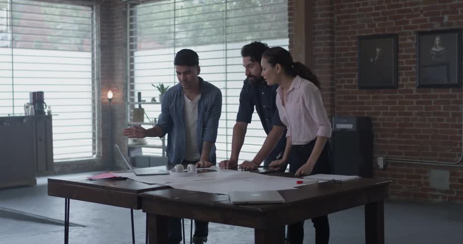 A group standing around a table pointing at a laptop and having a discussion