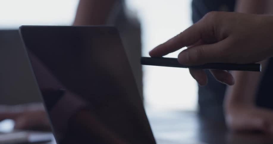 Two people stand near a table with a laptop on it