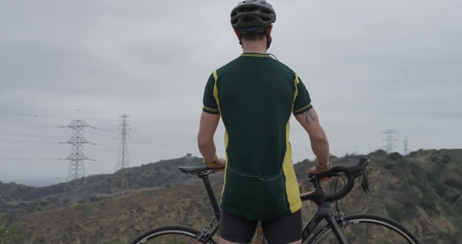 A man standing next to a bicycle out in the mountains