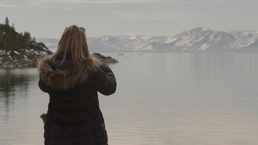 A woman is standing outside taking pictures on her phone