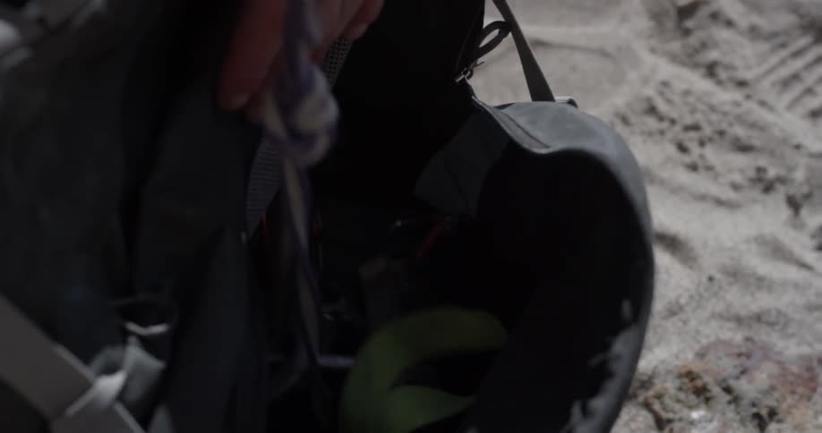 A person picks up a book bag and pulls a purse out of it