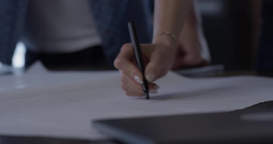 A person drawing on a piece of paper with a pen