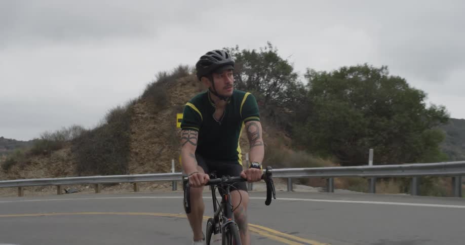 A man that is riding a bicycle up a hill