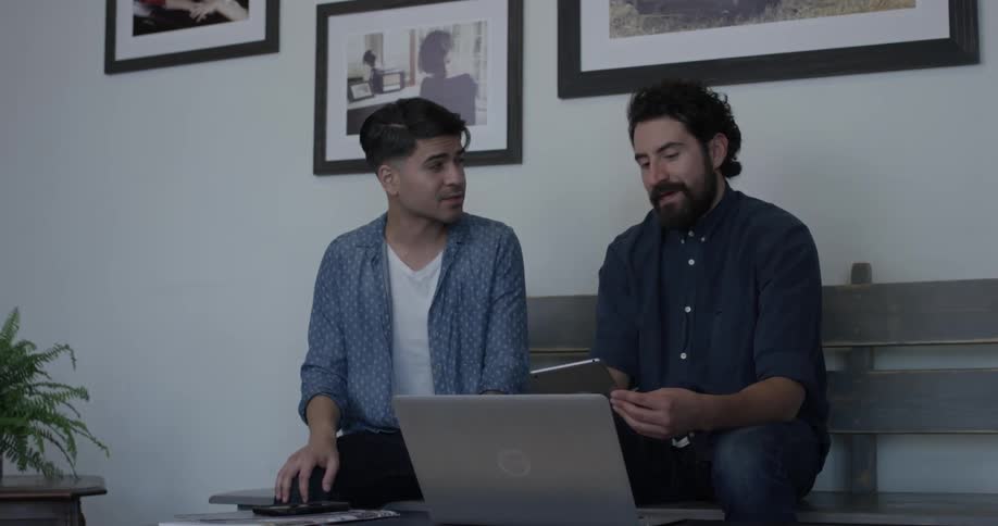 Two men talk and discuss something they are looking at on a tablet