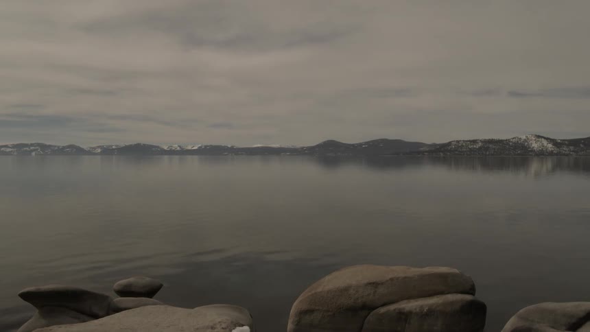 Snow dusted mountains and ground surrounding a lake