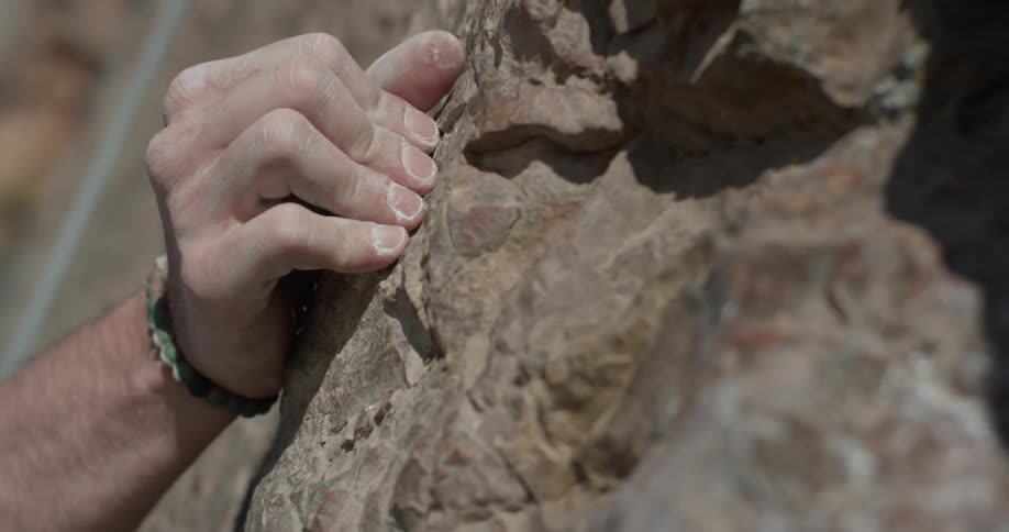 A man reaching for some rocks that he is climbing up