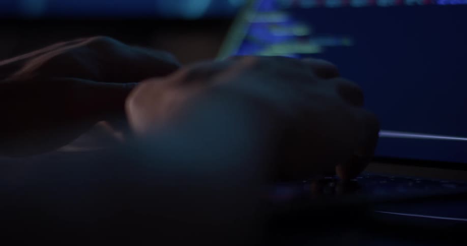 Man types on laptop while sitting