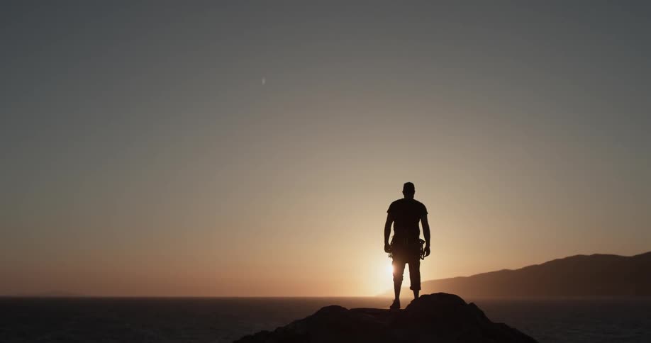 Silhouette of a man overlooking the ocean at sunset