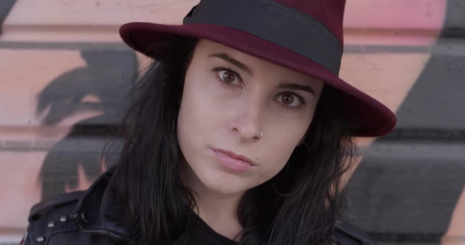 A woman wearing a hat and staring into the distance