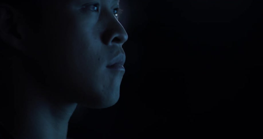 A man that is reading something in a dark room