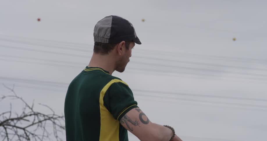 A cyclist undoes the strap on his helmet and takes the helmet off as he looks into the distance