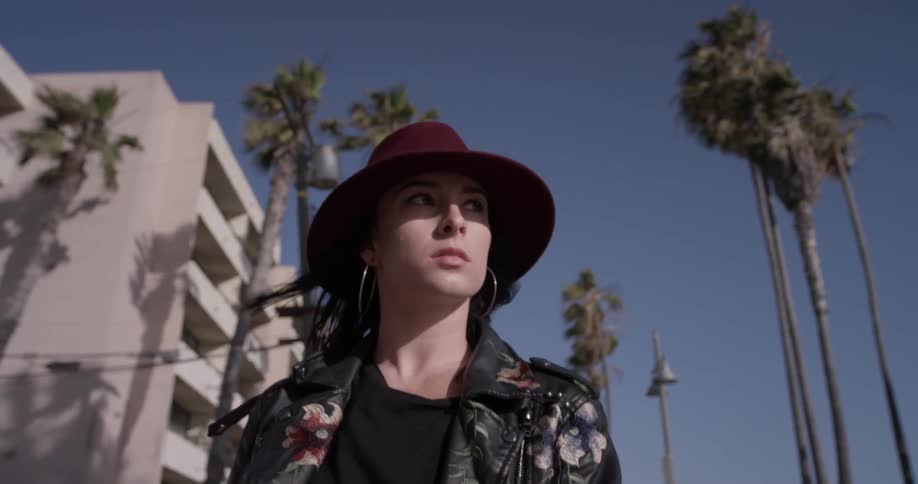 Woman with hat walking down the street with palm trees