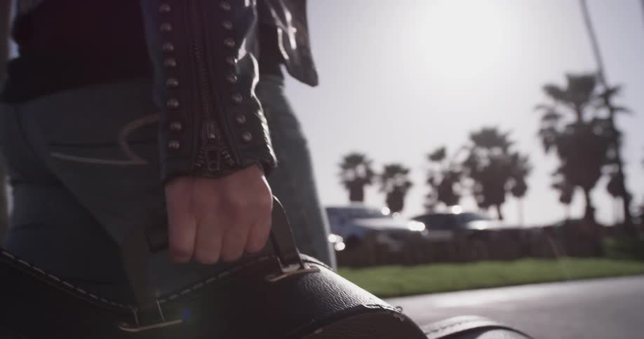 A person walking and carrying a guitar case