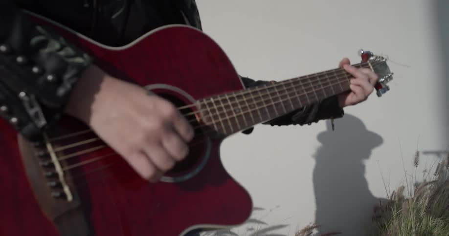 Close up of woman playing a red acoustic guitar