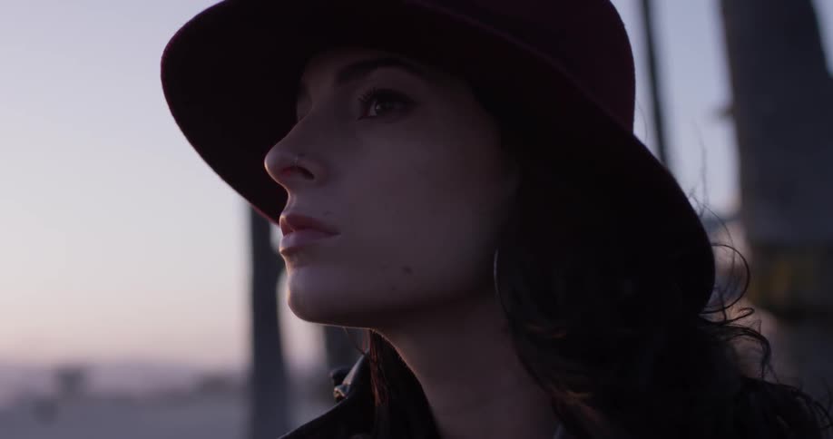 A woman stands looking into the distance as the wind blows her hair