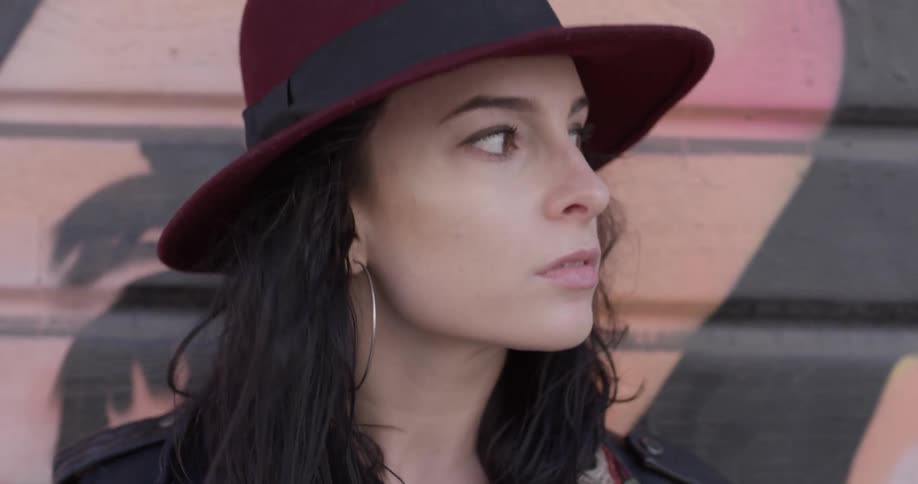 A head shot of a woman wearing a hat and looking around