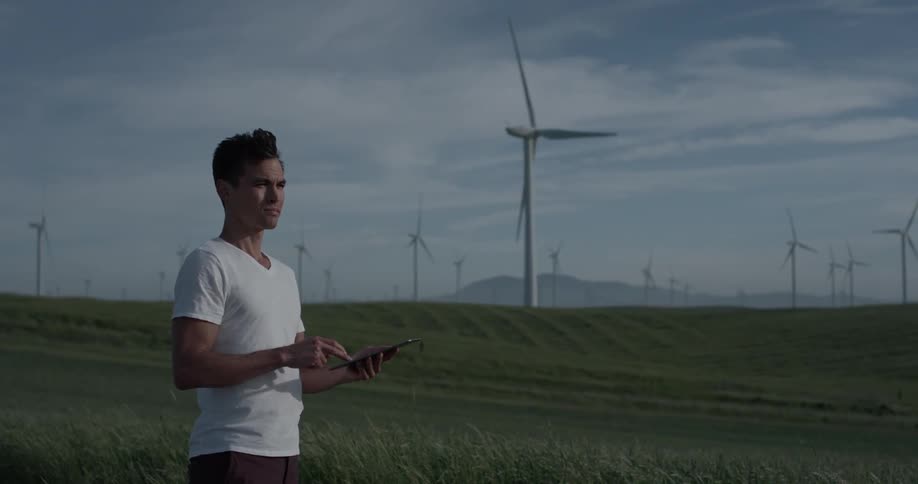 Man Driving Electric Car Through Wind Farm