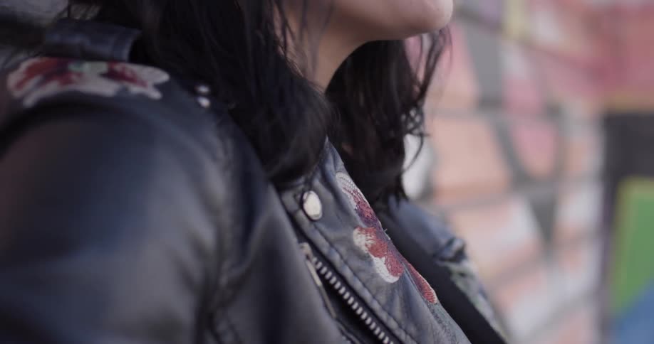 A woman that is singing next to a wall on the sidewalk