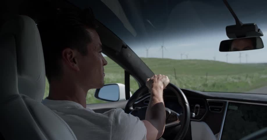 A man is driving a car by the countryside