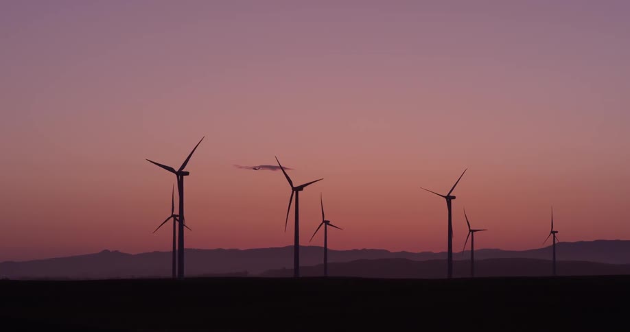 A group of windmills rotating at sunset