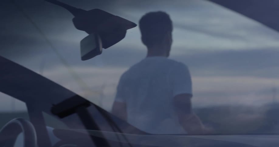 Man Driving Electric Car Through Wind Farm