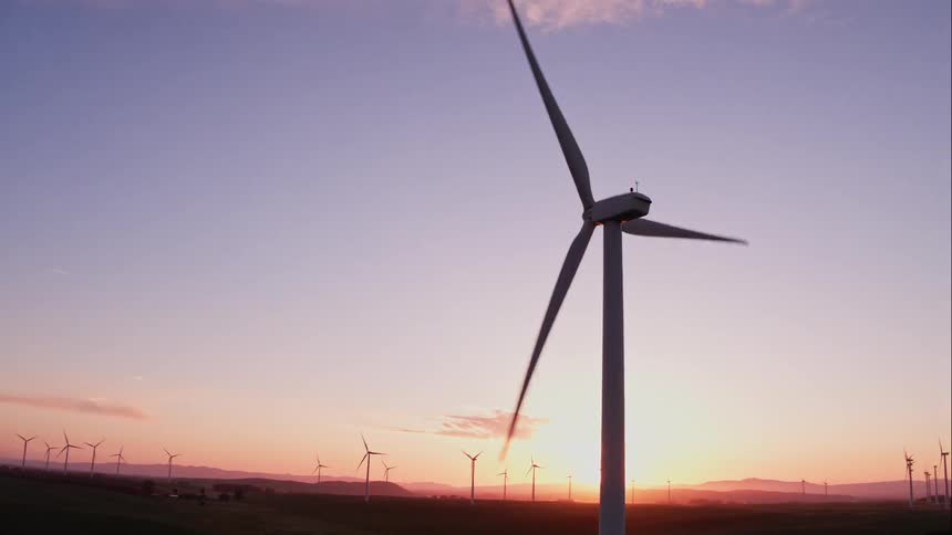 Man Driving Electric Car Through Wind Farm