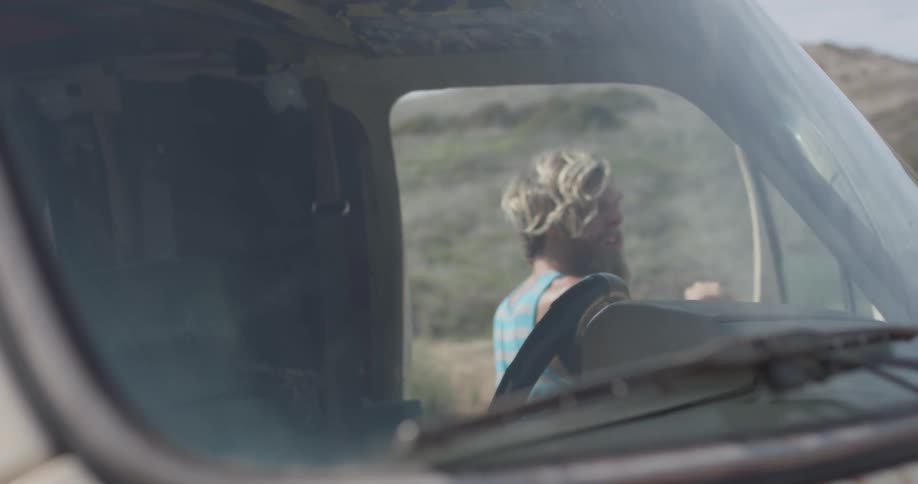 A scruffy man gets out of a van then closes the door