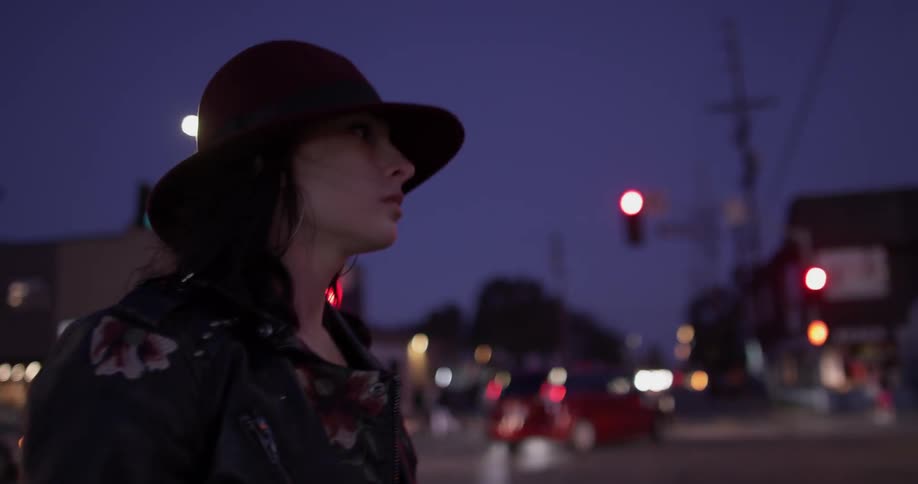 Woman walks down city sidewalk at night