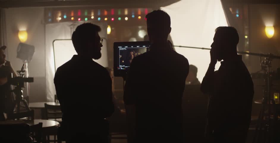 Men on a film set looking at a monitor and having a discussion