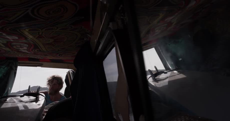A man pulling a surfboard out of the back of a van
