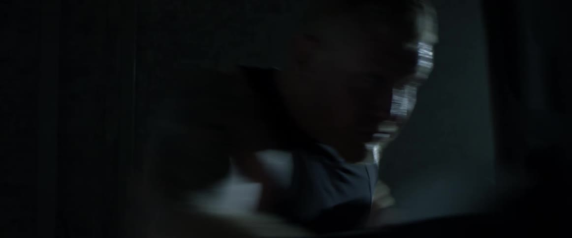 A man is practicing punching a punching bag while wearing gloves and a spotlight shines on him