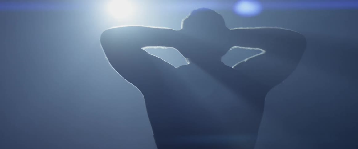 A man grabs the back of his head walking toward a bright light