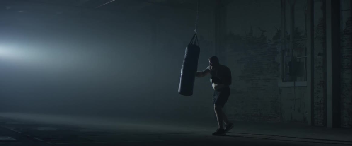 Man boxing a heavy bag in an empty room